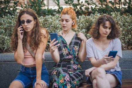 Alienation addiction. Group of girlfriends using smartphones together. Young people addiction to new technology trends. Youth, new generation internet friendship concept. Emotional isolation and depresionの写真素材