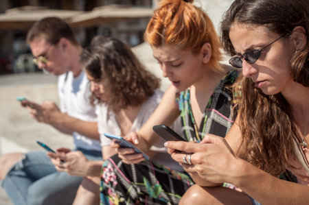Alienation addiction. Group of friends using smartphones together. Young people addiction to new...