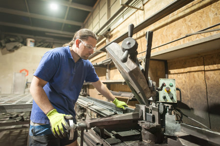 Metal works. Worker using electric wheel grinding on steel structure in factory