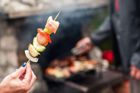 Man cooking meat on barbecue grill at bbq party in summer garden. Food, people and family time conceptの写真素材