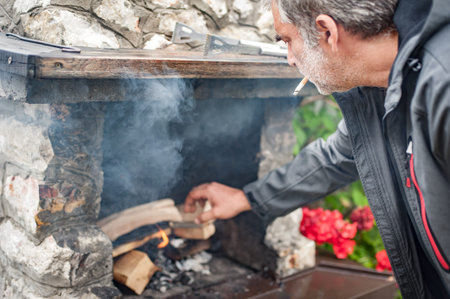 Barbecue. Man in the countryside burns dry branches to make charcoal ready for grill. BBQ grilling...