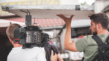 Behind the scenes. Film crew team shooting movie scene on outdoor location. Group filmmaking set...
