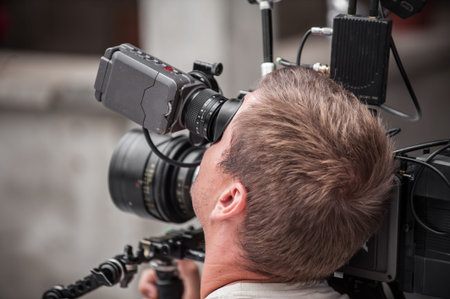 Behind the scene. Cameraman shooting the film scene with his camera on outdoor set. Photography...