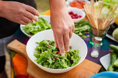 Preparation vegetable salad. Woman preparing food on table at backyard. Making vegetarian foodの写真素材