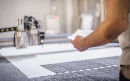 Factory worker technician works on large CNC digital cutter machine for cutting fabric textile materialの写真素材
