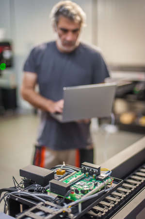 Field service maintenance engineer technician electrician inspect and control machine hardware and software system with laptop computer. Electric installationの写真素材