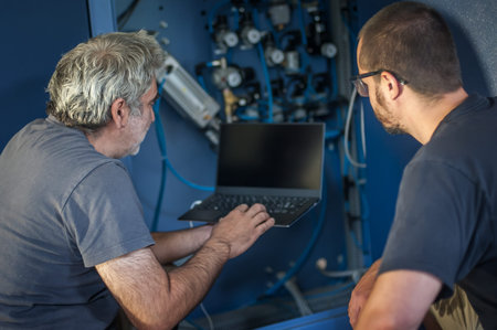 Two field service maintenance engineer technician electrician inspect and control machine hardware...
