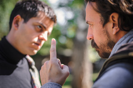Close-up finger pointing of two very angry, nervous and upset men in an aggressive and fierce quarrel conflict on the verge of a physical confrontation and a fight. Concept of male conflictの写真素材