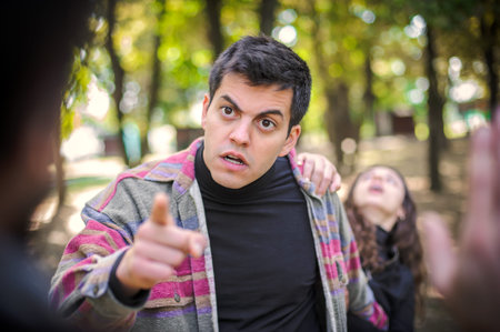 Two aggressive, angry, nervous and upset men in a quarrel and a woman who trying to prevent a conflict. Finger pointing. Group quarrel conceptの写真素材