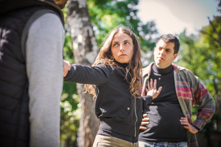 The woman tries to separate the two aggressive, angry, nervous and upset men in quarrel and stands...