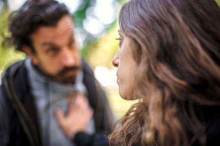 Bully and abuser, a jealous boyfriend abuses his girl girlfriend, verbally and physically threatens, yells at her and scares her, outdoor in public park. Domestic violence conceptの写真素材