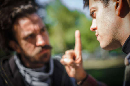 Close-up finger pointing of two very angry, nervous and upset men in an aggressive and fierce quarrel conflict on the verge of a physical confrontation and a fight. Concept of male conflictの写真素材