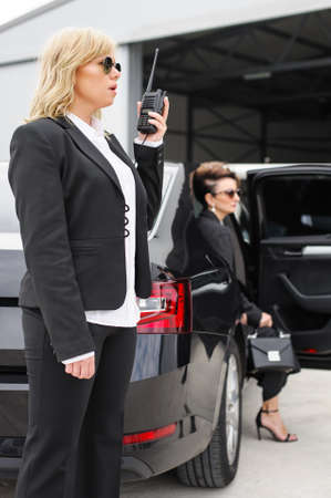 Female Bodyguard with walkie talkie. Celebrity and VIP person security close protection services. Professional police agent special forces in civilian black suitの写真素材