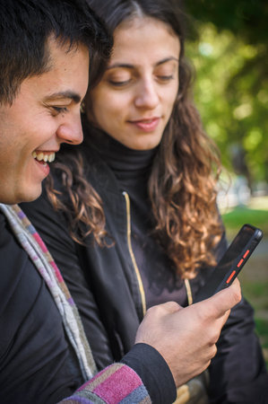 A young smiling couple in love, a boyfriend and a girlfriend, looks at photos together and reads...