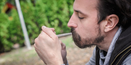 Man lighting up a joint a marihuana or hashish joint cigarette. Closeup detail view. Young people smoke cannabis thc grass. Real life scene conceptの写真素材
