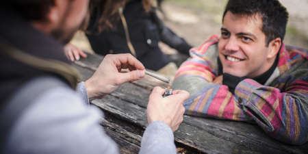 Man heats and lights marihuana or hashish joint cigarette to burn better. Closeup detail view. Young people smoke cannabis thc grass. Real life scene conceptの写真素材