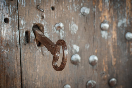 Closeup detail view of old massive metal key in a large huge church wooden ancient door. Secret...