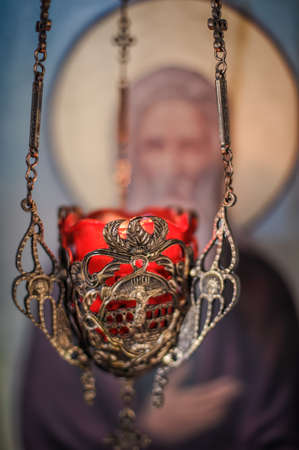 Close up detail view of christian hanging oil candle of brass and glass, hanging in church in front of religious iconography and iconostasisの素材 [FY310179315503]