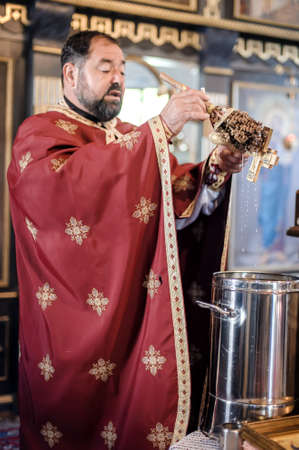 Holy water consecration in orthodox church. Religious priest during church service. Authentic religion spiritual ceremony. Faith, hope, spirit and peace ritual. Real life sceneの写真素材