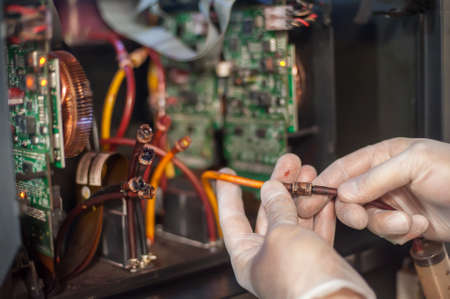 Closeup detail view of electrical engineer operator repairs large premium industrial printer and plotter machine in digital printshop officeの写真素材