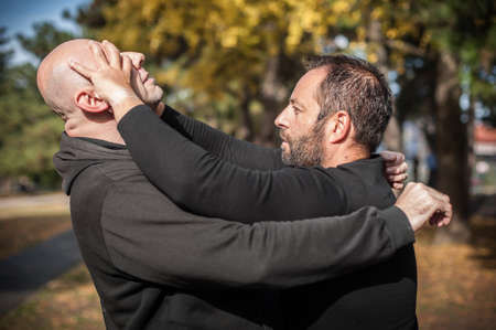 Kapap instructor demonstrates street fighting self defense technique against holds and grabs with his studentの写真素材
