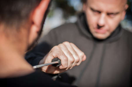 Knife threat. Kapap instructor demonstrates martial arts self defense disarming technique against knife attack. Weapon disarm training. Demonstration with plastic knifeの写真素材