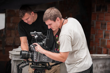 Behind the scenes. Cameraman shooting the film scene with camera on outdoor set. Photography...