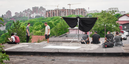 Behind the scenes. Film crew team takes a break and rest from filming on outdoor location set. Group filmmaking set productionの写真素材