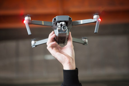 Hand holding photography and videography FPV flying drone copter in the air. Photography and...