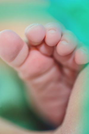 Close-up detail abstract macro view of cute baby small leg foot fingers in green and turquoise color