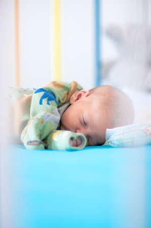 Cute little peaceful baby calm sleeps soundly in his crib with his baby toys in a bright room. Close-up portrait of beautiful child sleeping and restingの写真素材