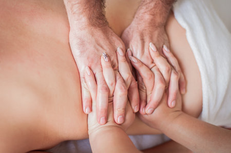 Closeup, back and hands double massage with four hands of two professional massagers for a young caucasian woman in a spa salonの写真素材