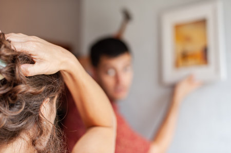 Young couple decorates their new apartment with painting on the wallの写真素材