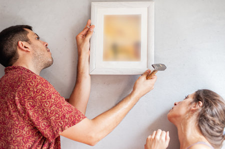 Young couple decorates their new apartment with painting on the wallの写真素材