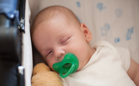 Close-up detail view of cute little peaceful baby calm sleeps soundly with pacifier in his crib....