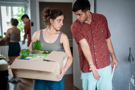 A young couple moves into their new apartment. They are surrounded by boxes, packages, colorful wardrobe and other things.の写真素材