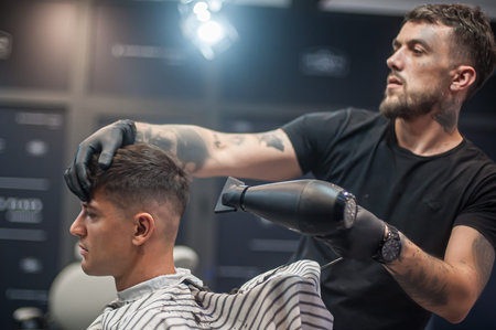 Modern urban hairdresser cut and adjusts the hairstyle in professional hairdressing salon and...
