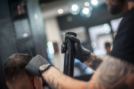 Modern urban hairdresser fixes the hairstyle with hairspray spray and drops are visible in the airの写真素材