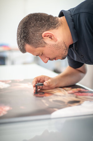 Young man in the process of printing used color scales and loupe and management color correction. Spectrophotometer, print measuring.の写真素材