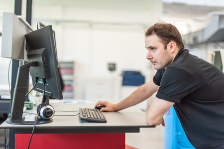 An experienced technician works on a printer computer in a printing shop. Production work. Check the...