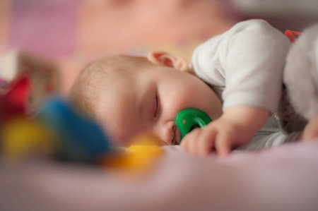 Close-up detail view of cute little peaceful baby calm sleeps soundly with pacifier in his crib....