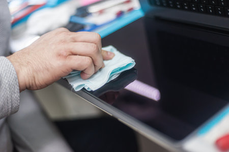 Close-up of specialized manual cleaning of laptop, screen, notebook, keyboard, case, from dust. Cleaning accessories: small vacuum cleaner, brush, cloth, spray.. Technical support and solving problems with gadgets. It is the service and maintenance of electronicsの写真素材