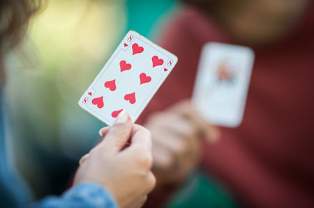 Card playing in a spring garden: Couple are sitting on a table, relaxing and playing cards together. Blurry background.の写真素材
