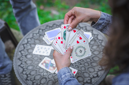 Card playing in a spring garden: Couple are sitting on a table, relaxing and playing cards together. Blurry background.の写真素材