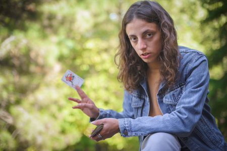 Playing cards in the spring garden. A woman plays cards and holds a joker in her hand.の写真素材
