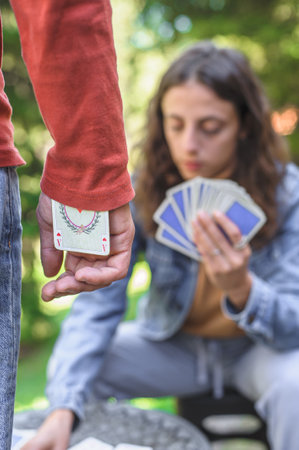 A young happy couple playing cards in a spring garden: the young man hides an ace in his sleeve.の写真素材