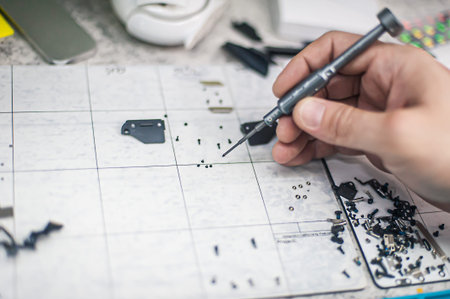Workplace top view, close-up. Repairman disassembles smartphone with screwdriver in an electronics...
