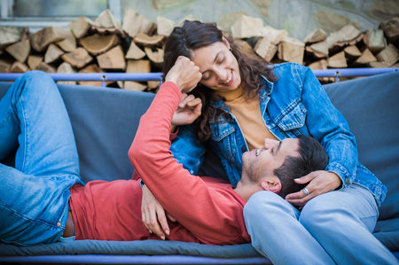 Cheerful and romantic couple is lying on a swing, hugging and enjoying in love. Love, relationship...