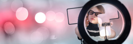 Young woman making photo or video content for social media with smartphone and light of ring lamp....