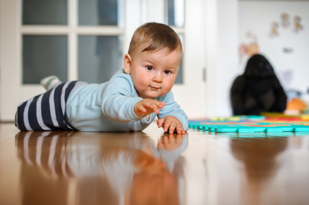 Cute baby boy crawls on the home floor, explore the world and learn to move. Love and family emotionの写真素材